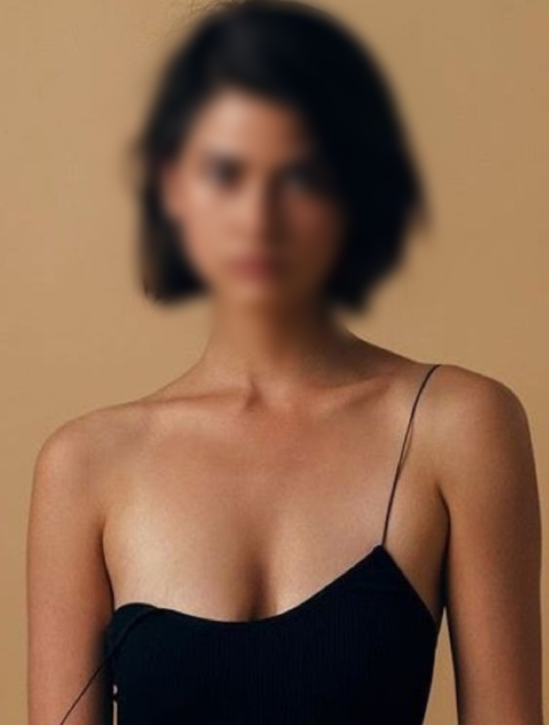 A young female model wearing a black dress with a bra top